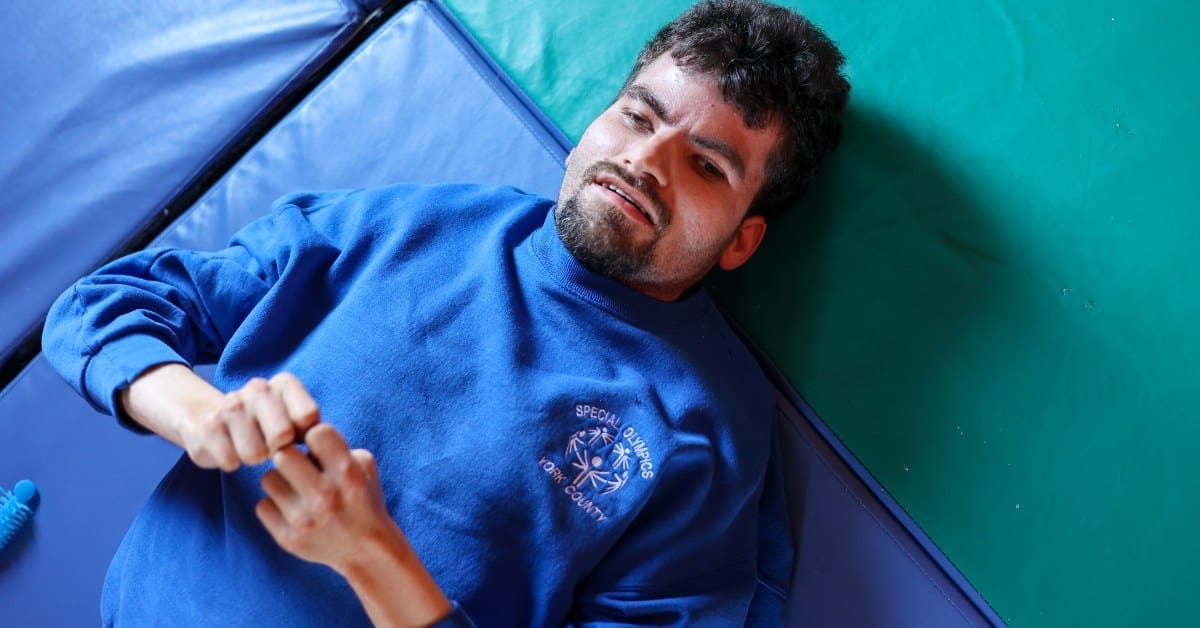 A TLC individual lays on a mat on the floor.