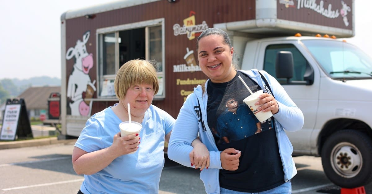 A TLC individual locks arms with a TLC Direct Support Professional as they enjoy milkshakes.