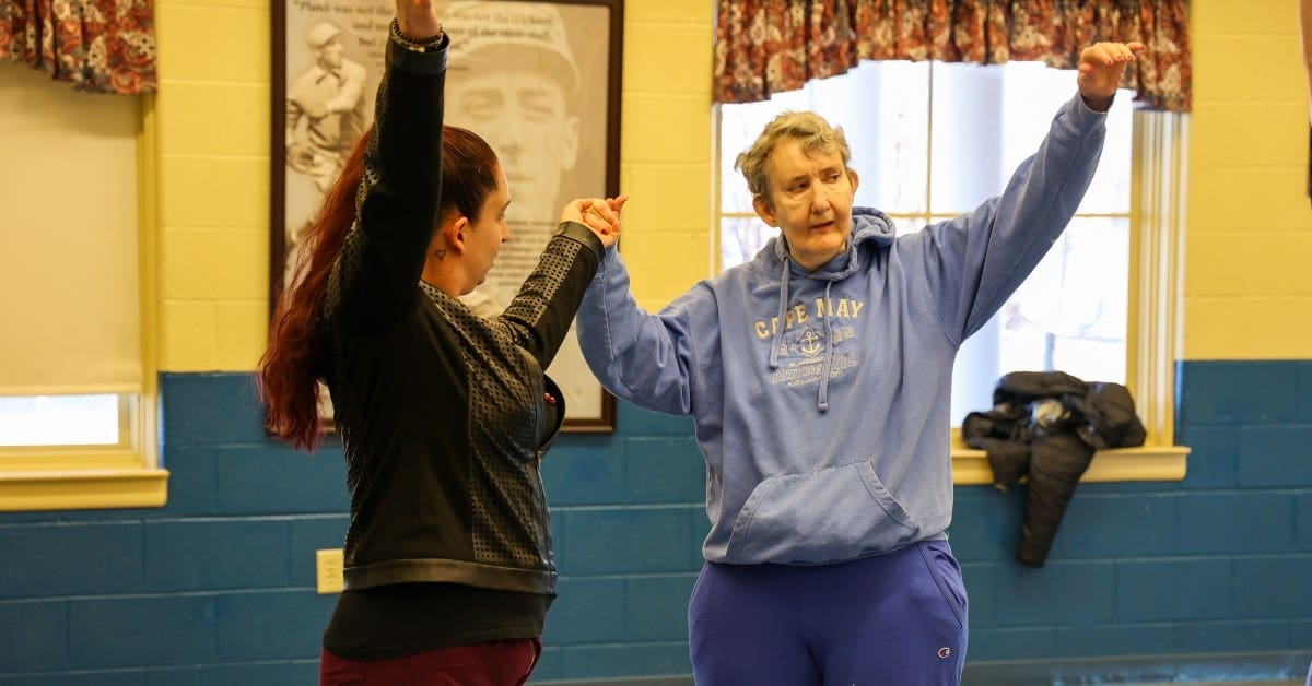 A TLC Direct Support Professional helps an individual stretch.