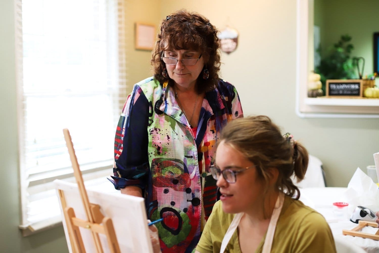 A TLC DSP looks over a TLC individual during a paint night session.