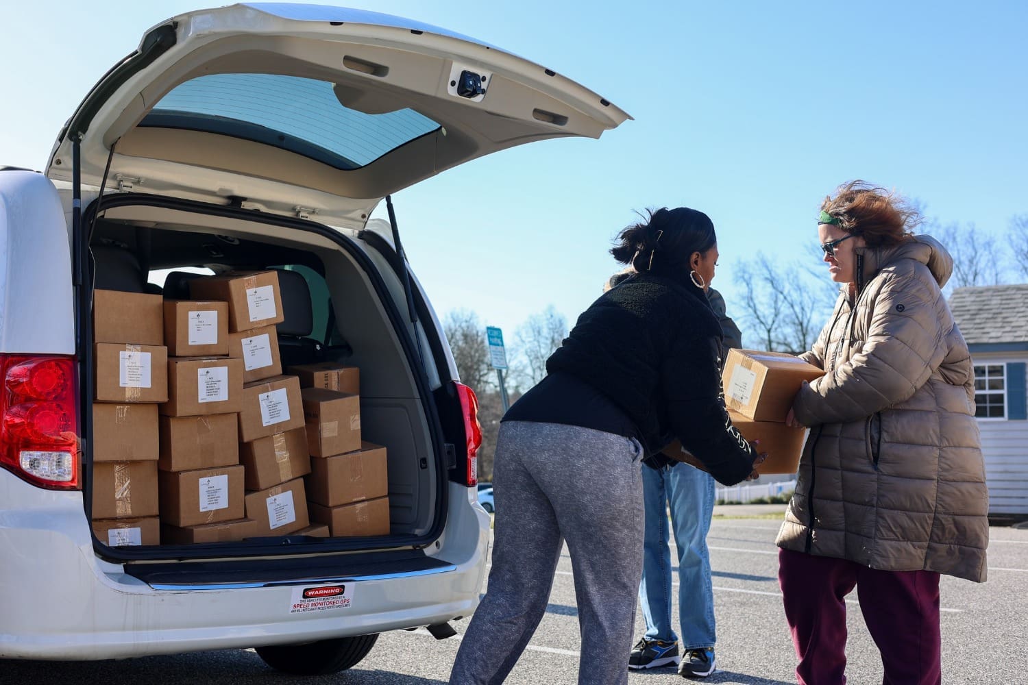 A TLC individual vacuums helps load boxes into a van.