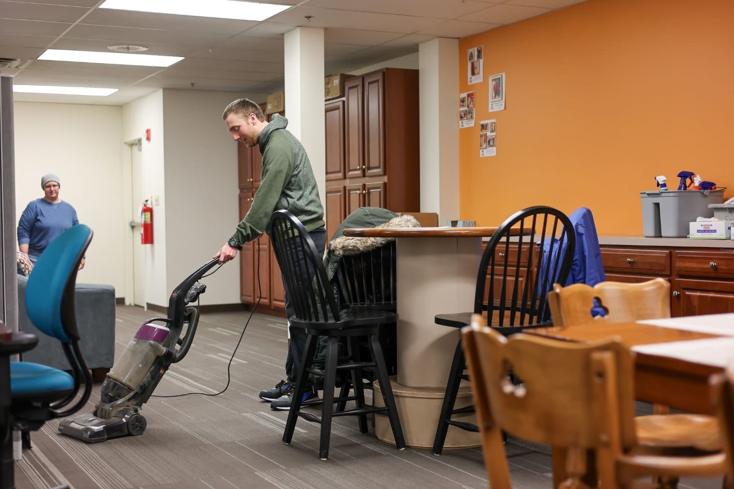 A TLC individual vacuums a community space floor.