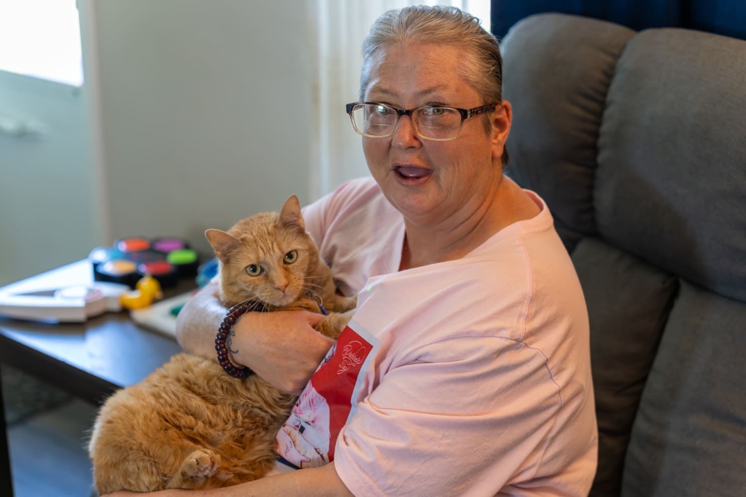 TLC resident Charro sits in a recliner holding her orange cat, Buttercup, in her lap.