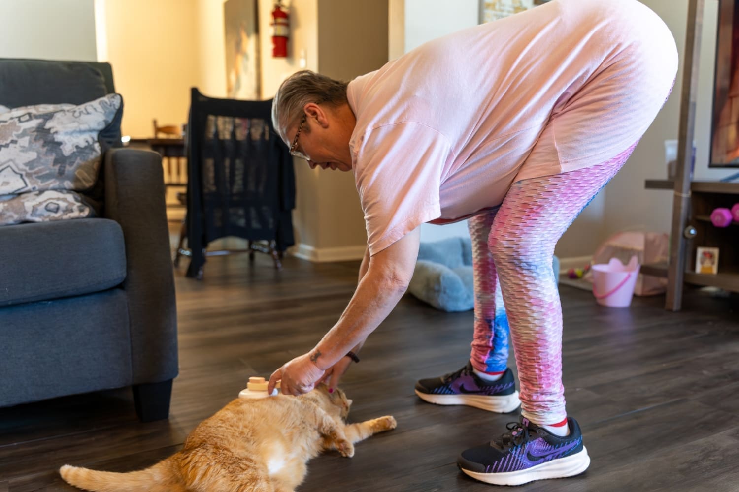 TLC resident Charro brushes her orange cat, Buttercup, as she lies on the floor of their home.