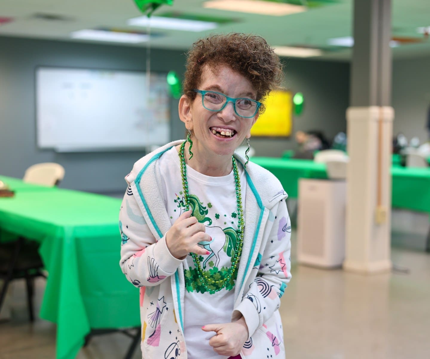 A TLC individual smiles for a photo at a St. Patrick's Day party.